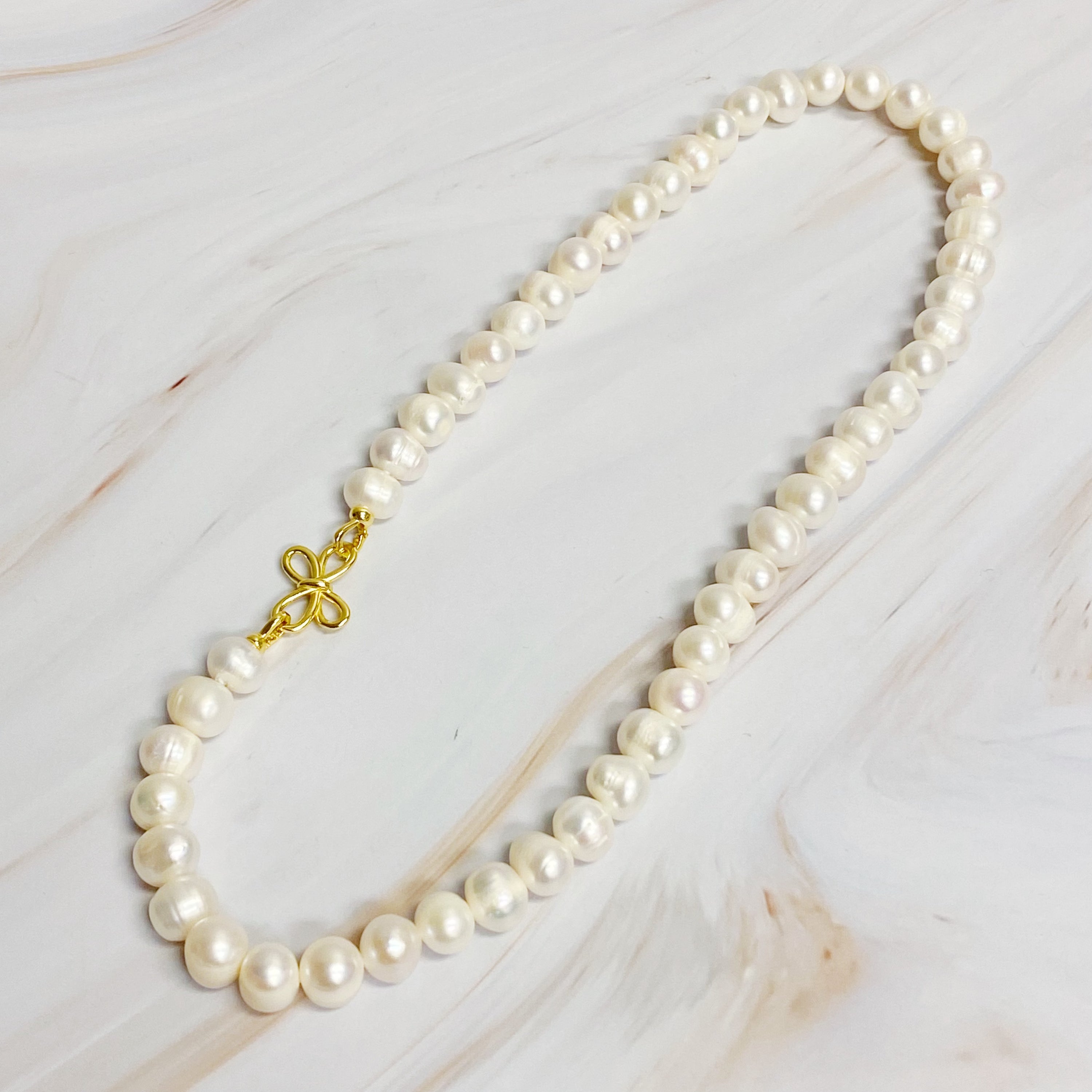 Clover Clasp Genuine Pearl Necklace featuring freshwater pearls in various sizes and an elegant 18k gold dipped sterling silver clasp.