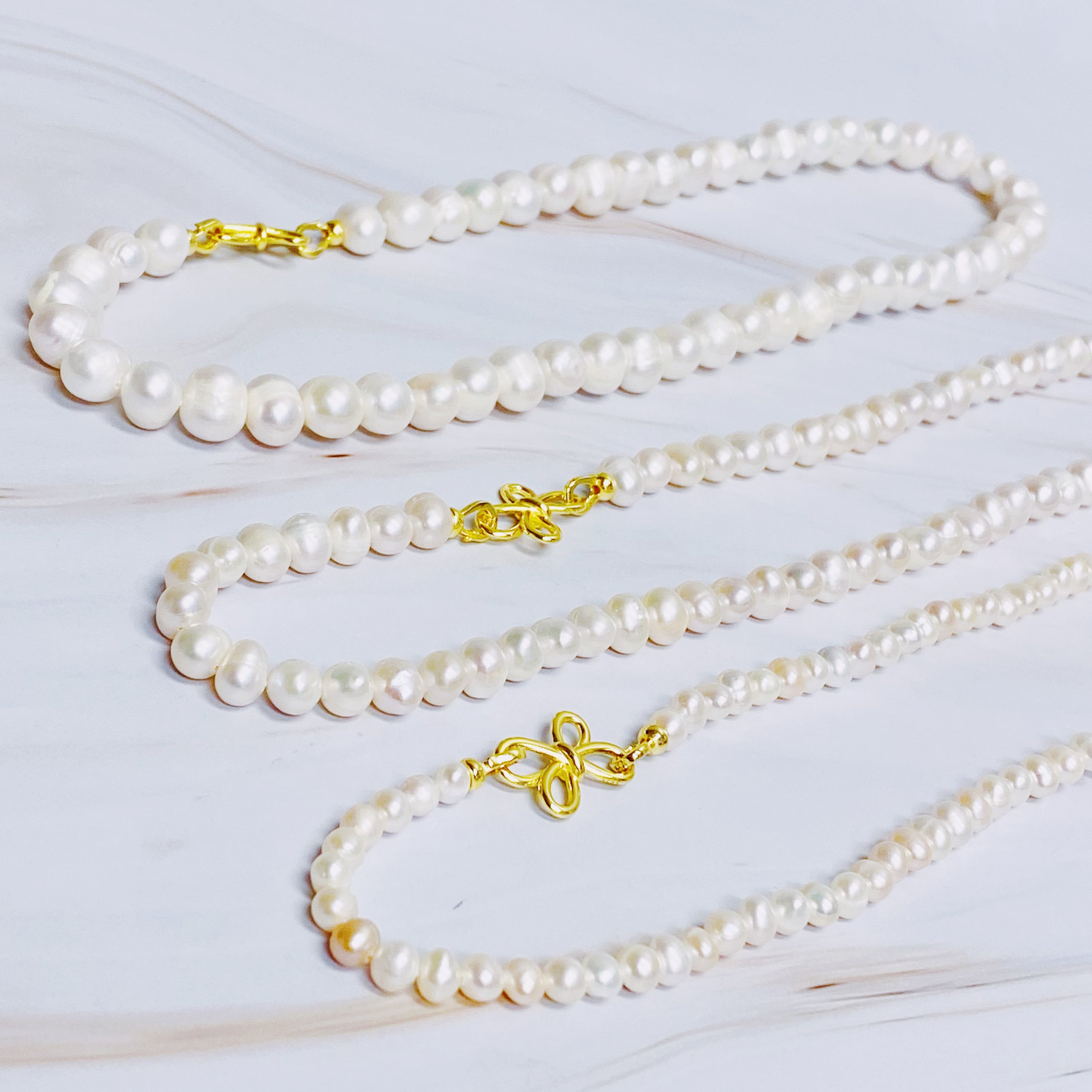 Clover Clasp Genuine Pearl Necklace featuring freshwater pearls in various sizes and an elegant 18k gold dipped sterling silver clasp.