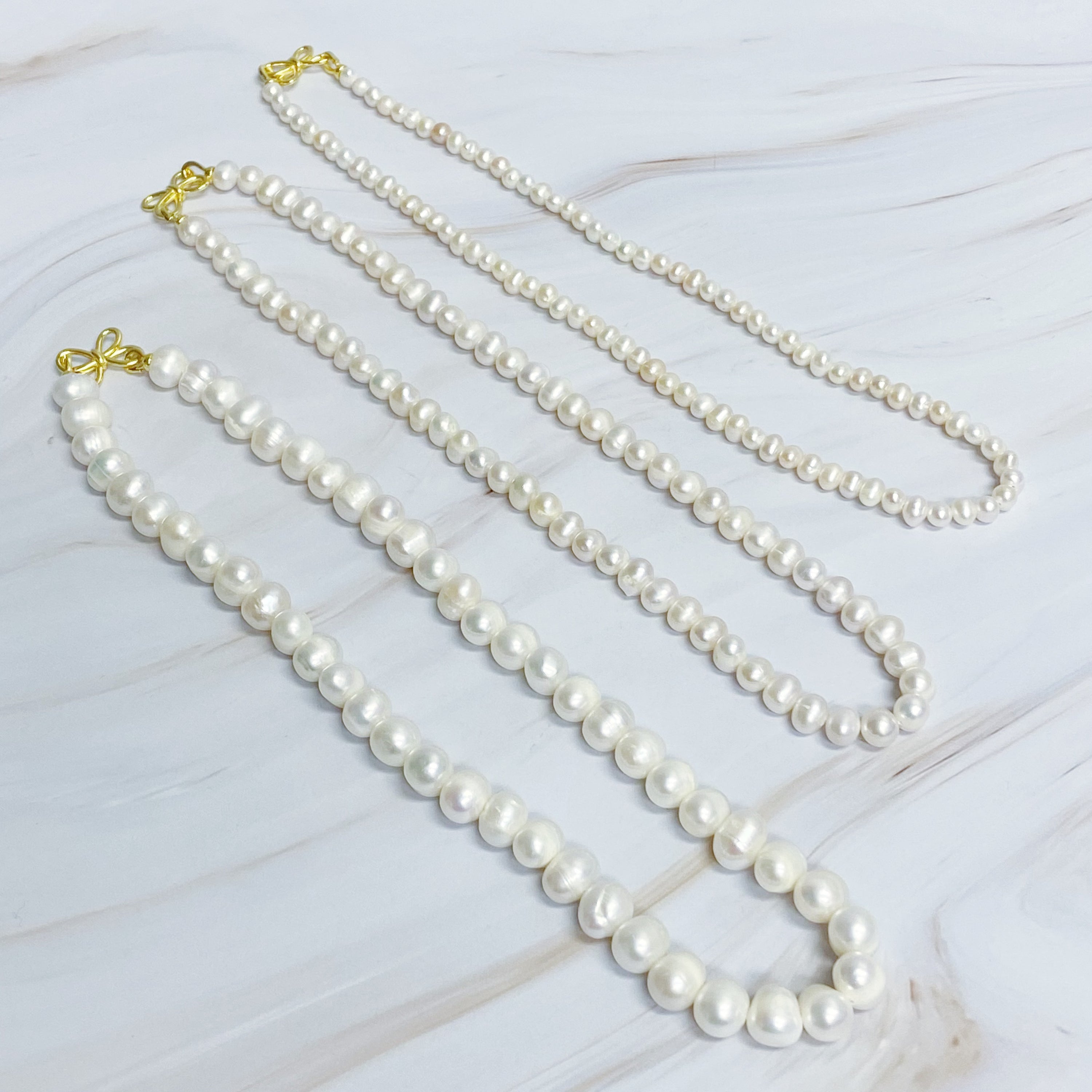 Clover Clasp Genuine Pearl Necklace featuring freshwater pearls in various sizes and an elegant 18k gold dipped sterling silver clasp.