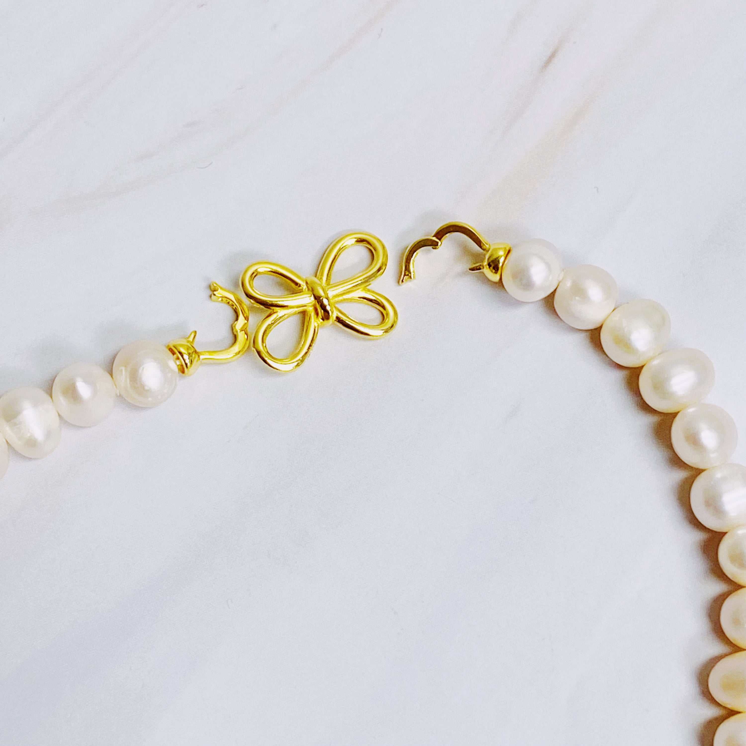 Clover Clasp Genuine Pearl Necklace featuring freshwater pearls in various sizes and an elegant 18k gold dipped sterling silver clasp.