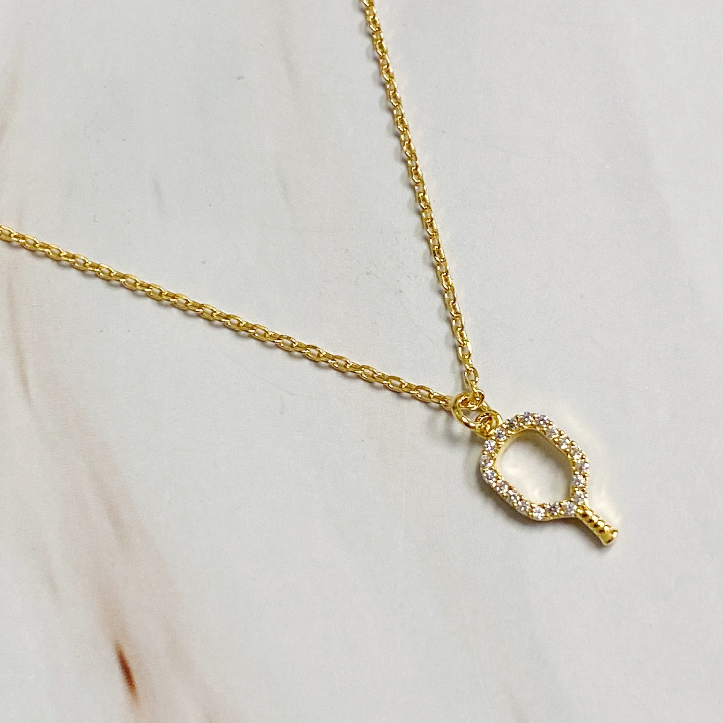 A delicate gold plated brass necklace featuring a pickleball racket outline, perfect for pickleball enthusiasts.