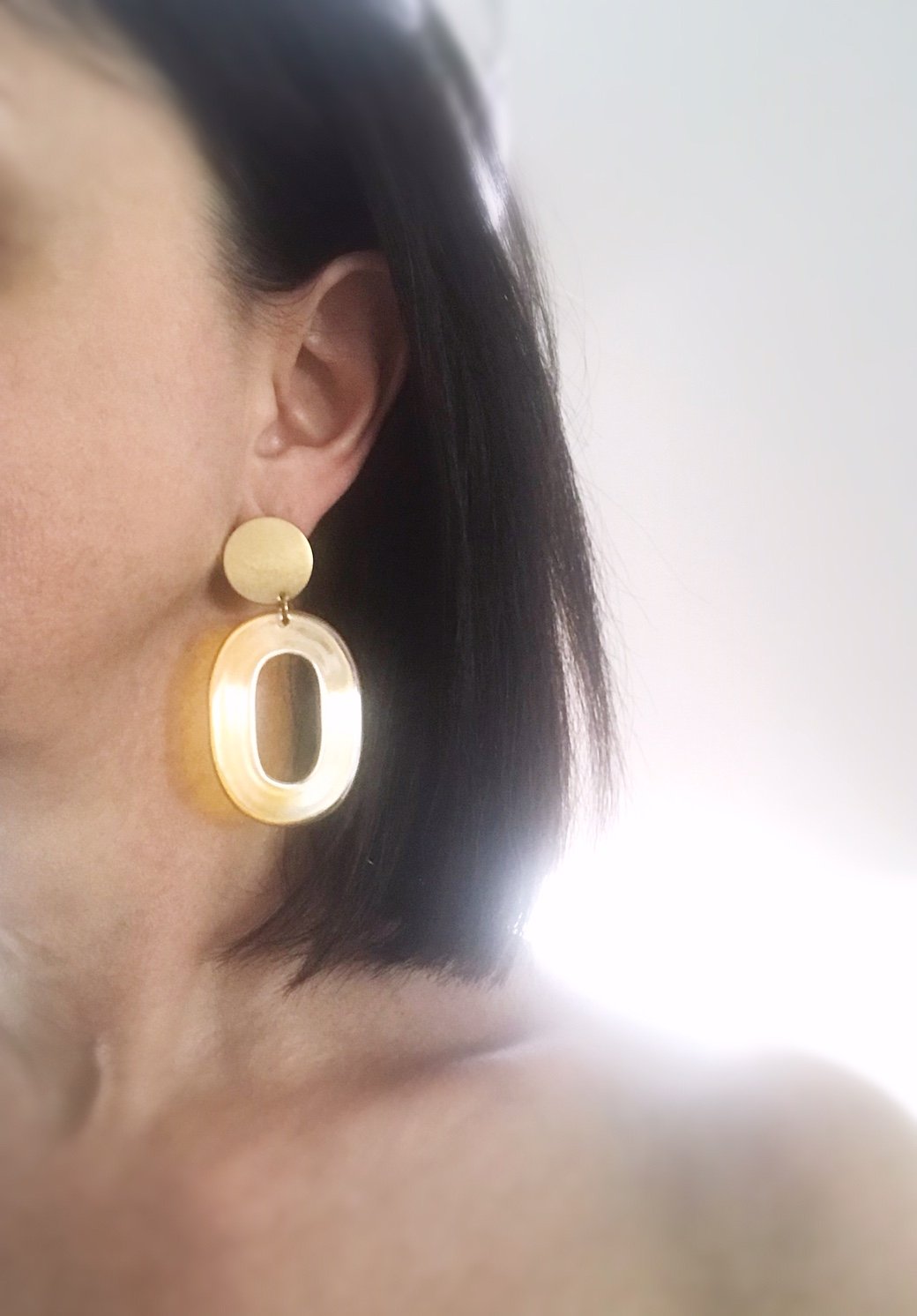 Coco earrings featuring large ivory acetate hoops and enameled brass discs, showcasing a stylish and lightweight design.