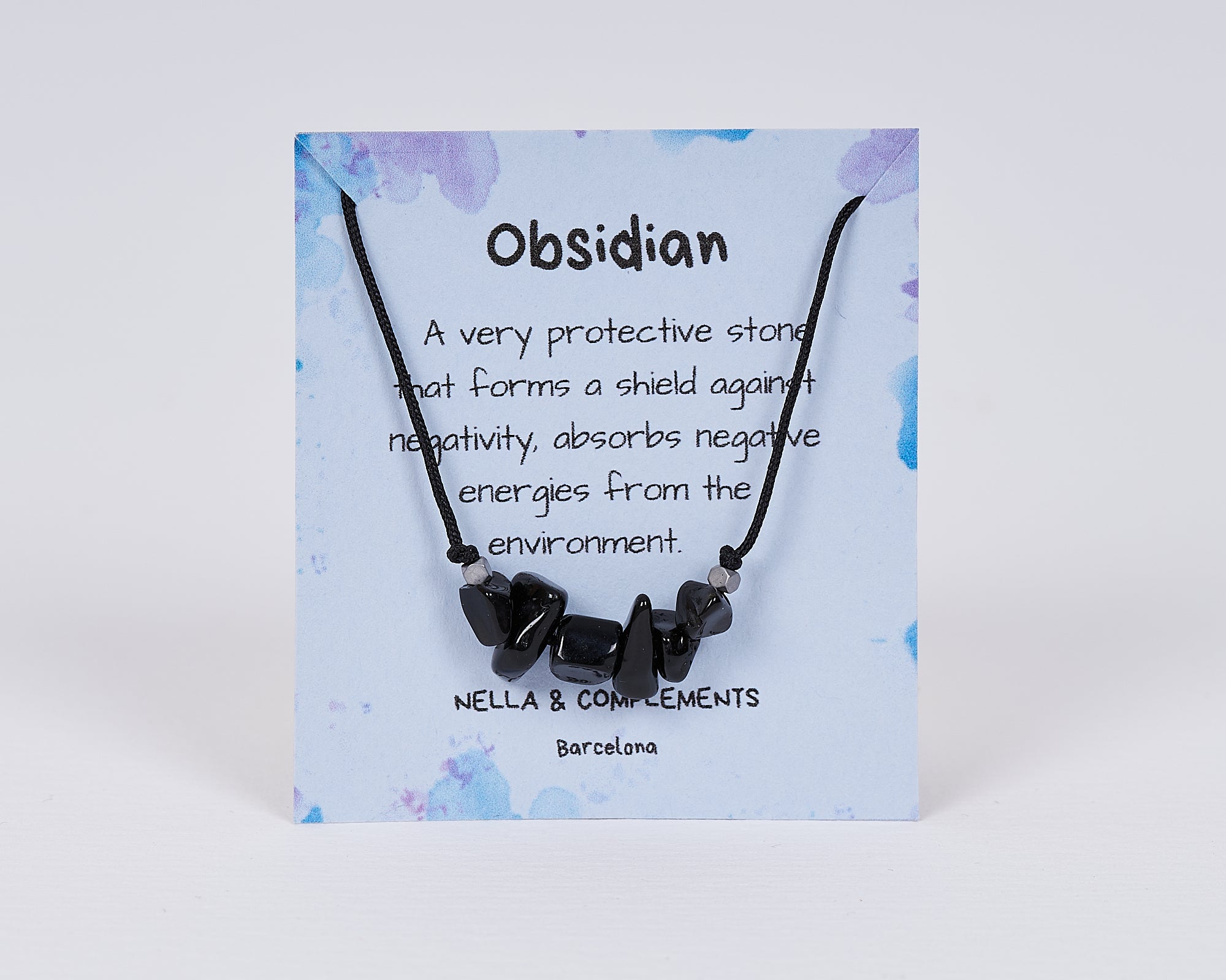 Collar de obsidiana natural hecho a mano, con colgante delicado y tarjeta descriptiva, ideal para protección y energía positiva.