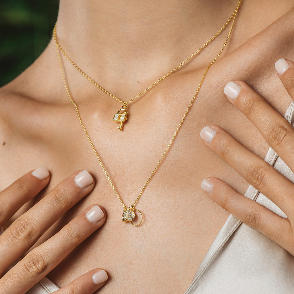 Collar elegante de plata bañada en oro amarillo con diseño de llave y candado, adornado con circonitas blancas brillantes.