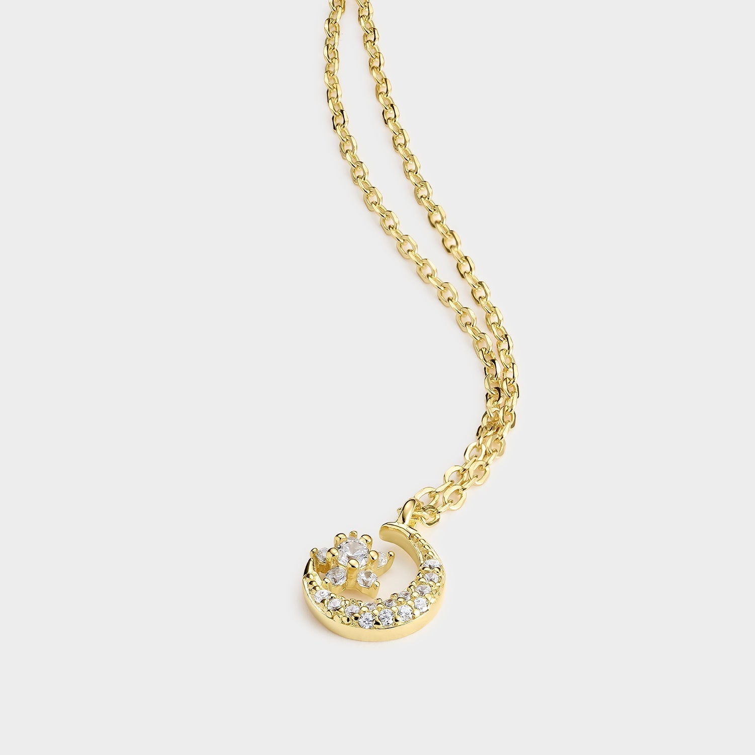 Collar de plata bañado en oro de 18K con colgante de luna y estrella, adornado con circonitas blancas, elegante y brillante.