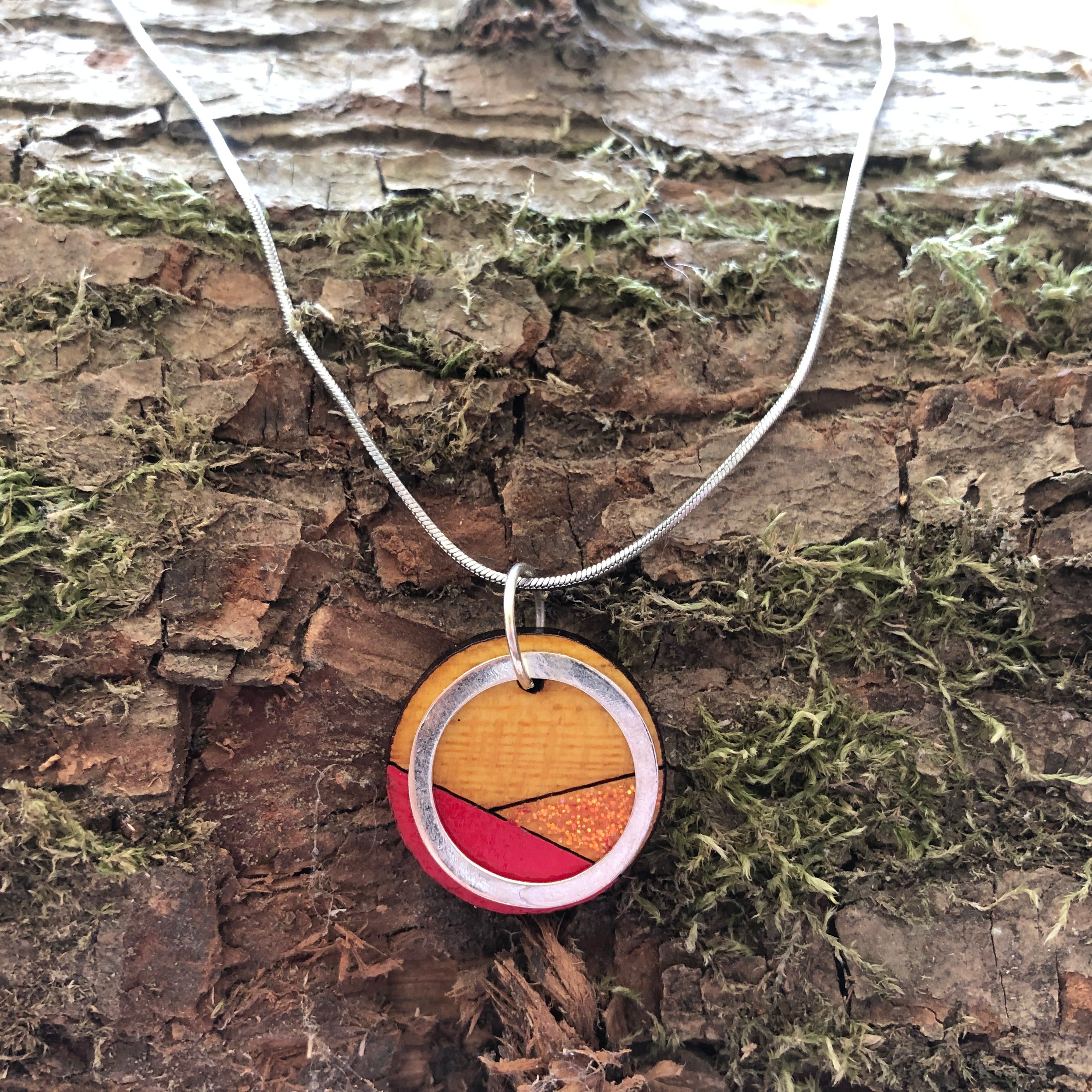 Conture Recycled Wood Silver Necklace showcasing vibrant colors and unique handcrafted design, featuring a silver titanium chain and brass ring.