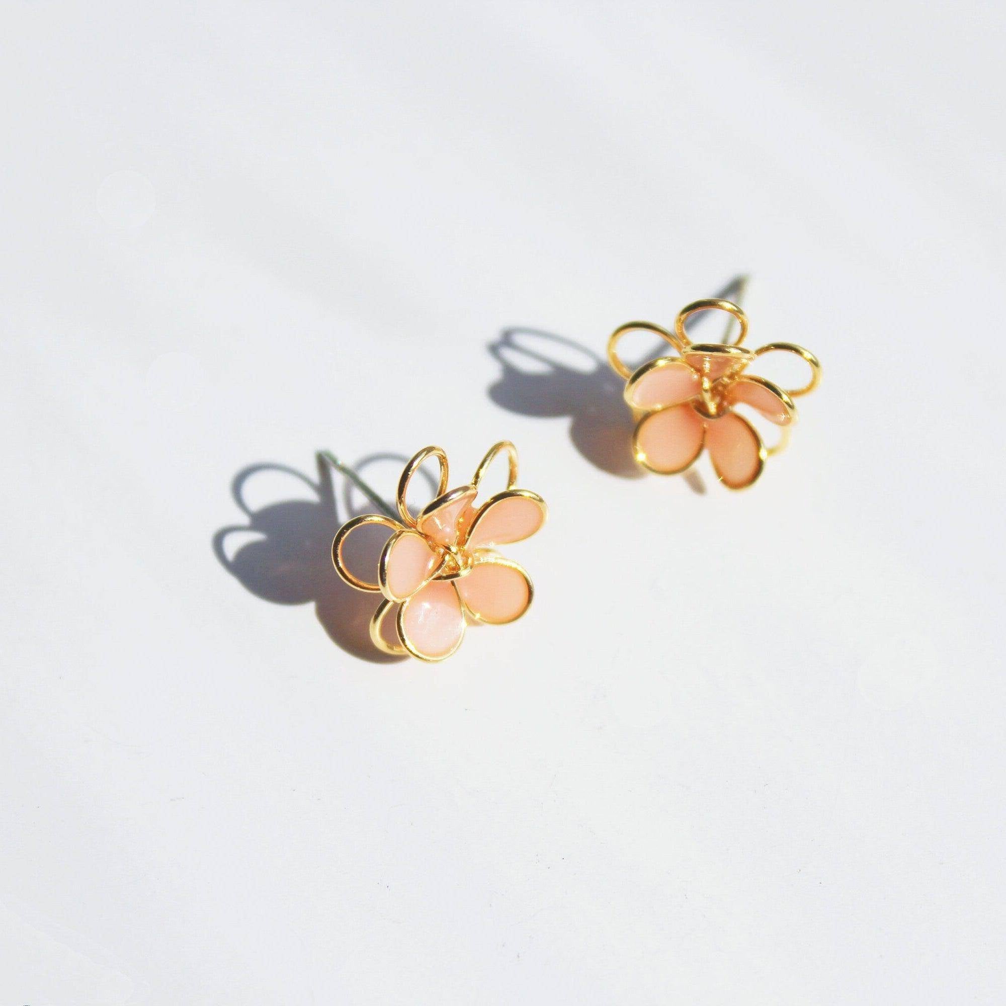 A pair of handmade orange cosmos flower earrings featuring double-layer design in gold wire and sterling silver studs, elegantly displayed.