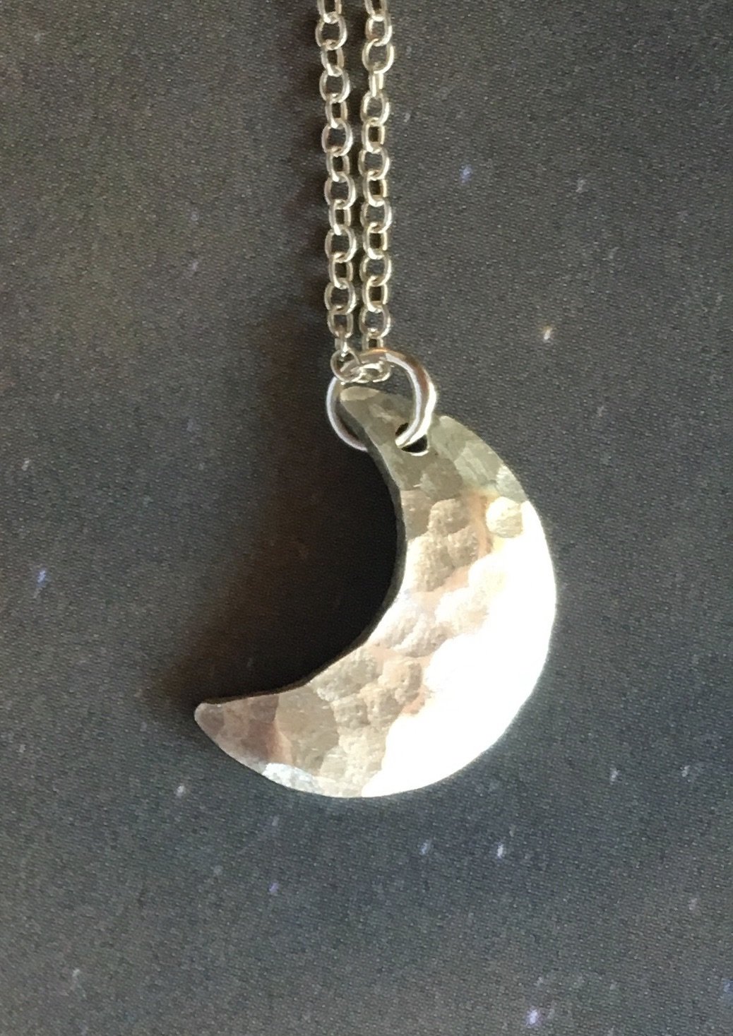 A beautifully handcrafted crescent moon necklace with a hammered texture, showcasing its unique design and sustainable materials.