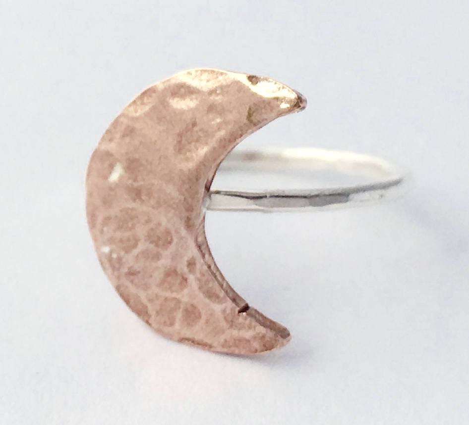 A handcrafted Crescent Moon Ring made from recycled metals, featuring a rustic design that mimics the moon's surface.