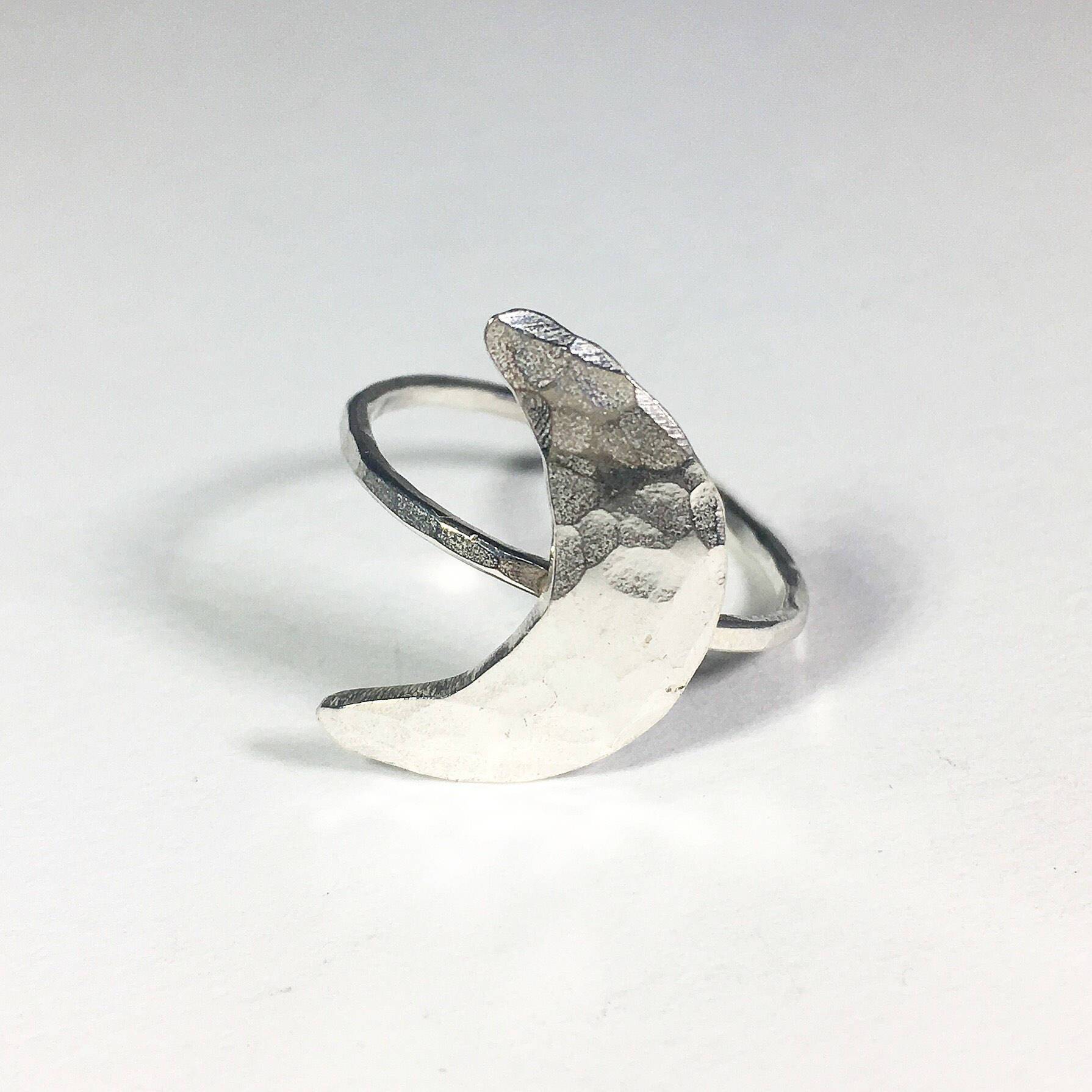 A handcrafted Crescent Moon Ring made from recycled metals, featuring a rustic design that mimics the moon's surface.