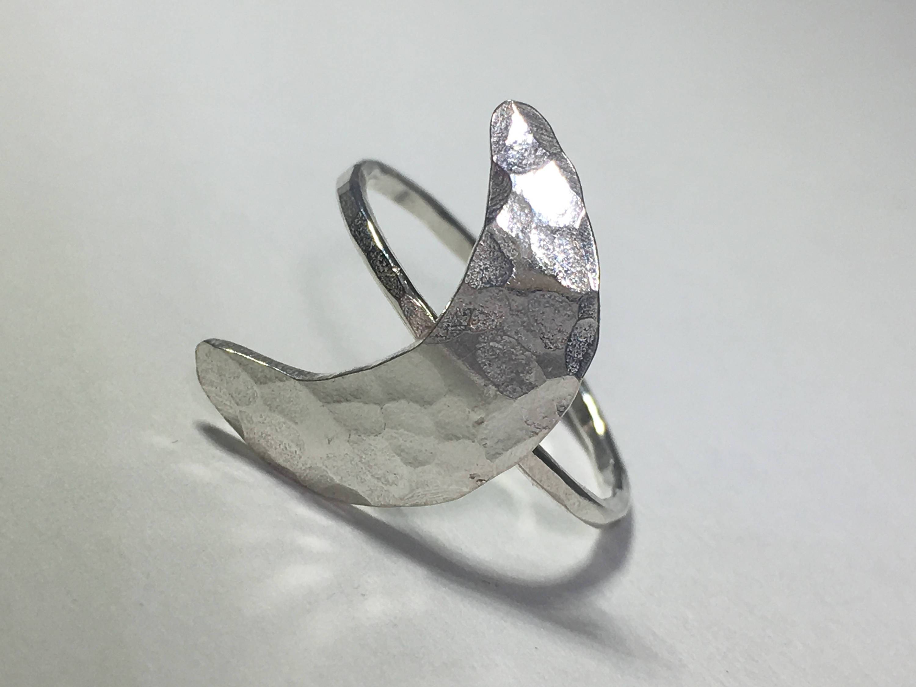 A handcrafted Crescent Moon Ring made from recycled metals, featuring a rustic design that mimics the moon's surface.