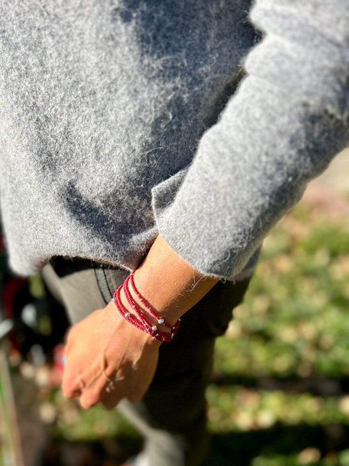 A vibrant crimson red and silver sprinkled beaded bracelet, showcasing a bohemian style with five wraps around the wrist.