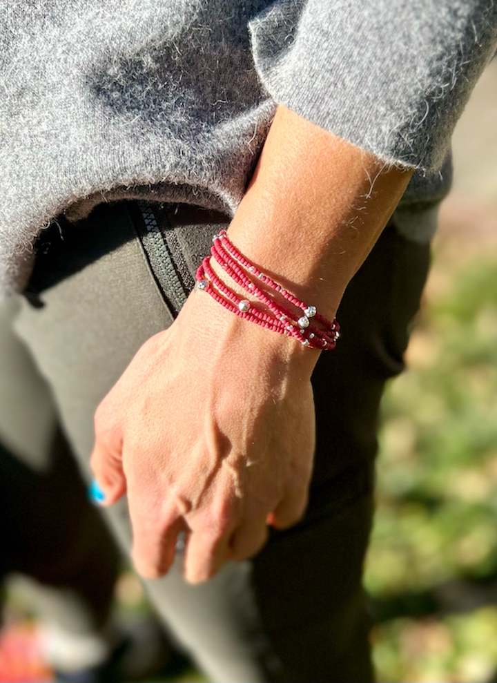 A vibrant crimson red and silver sprinkled beaded bracelet, showcasing a bohemian style with five wraps around the wrist.