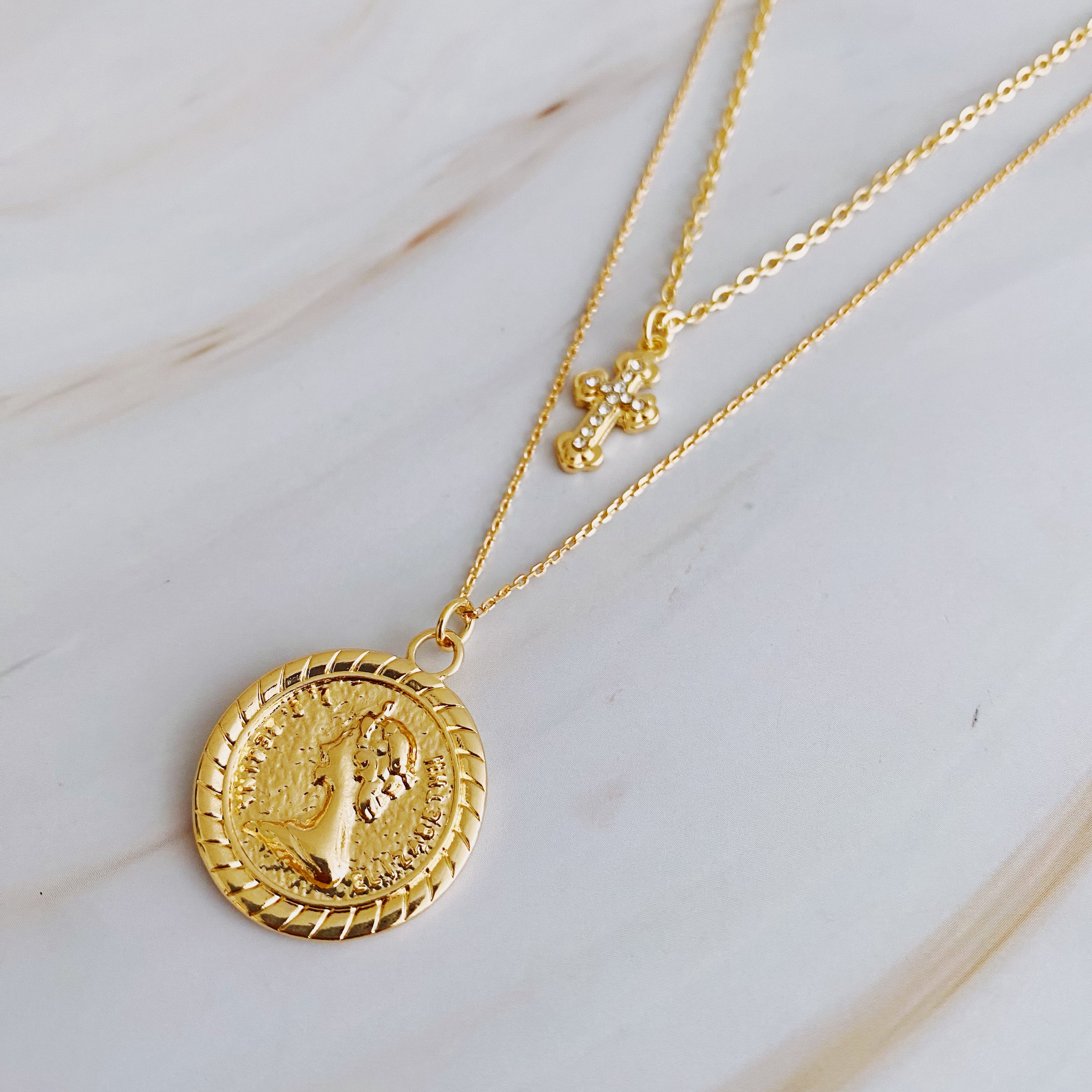 Cross and Coin Layered Necklace featuring a gold plated cross and classic coin design, elegantly layered for a stylish look.