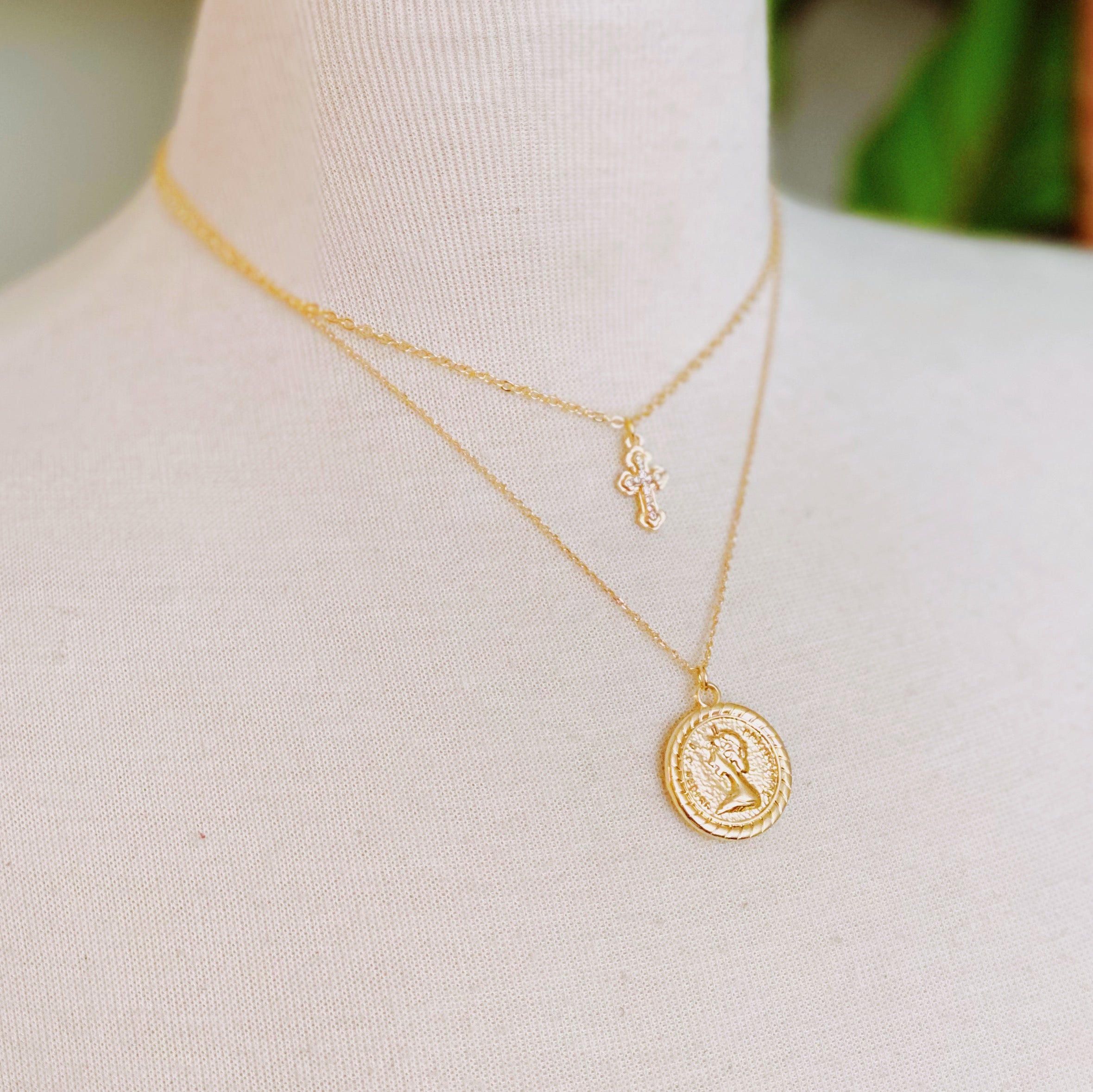 Cross and Coin Layered Necklace featuring a gold plated cross and classic coin design, elegantly layered for a stylish look.