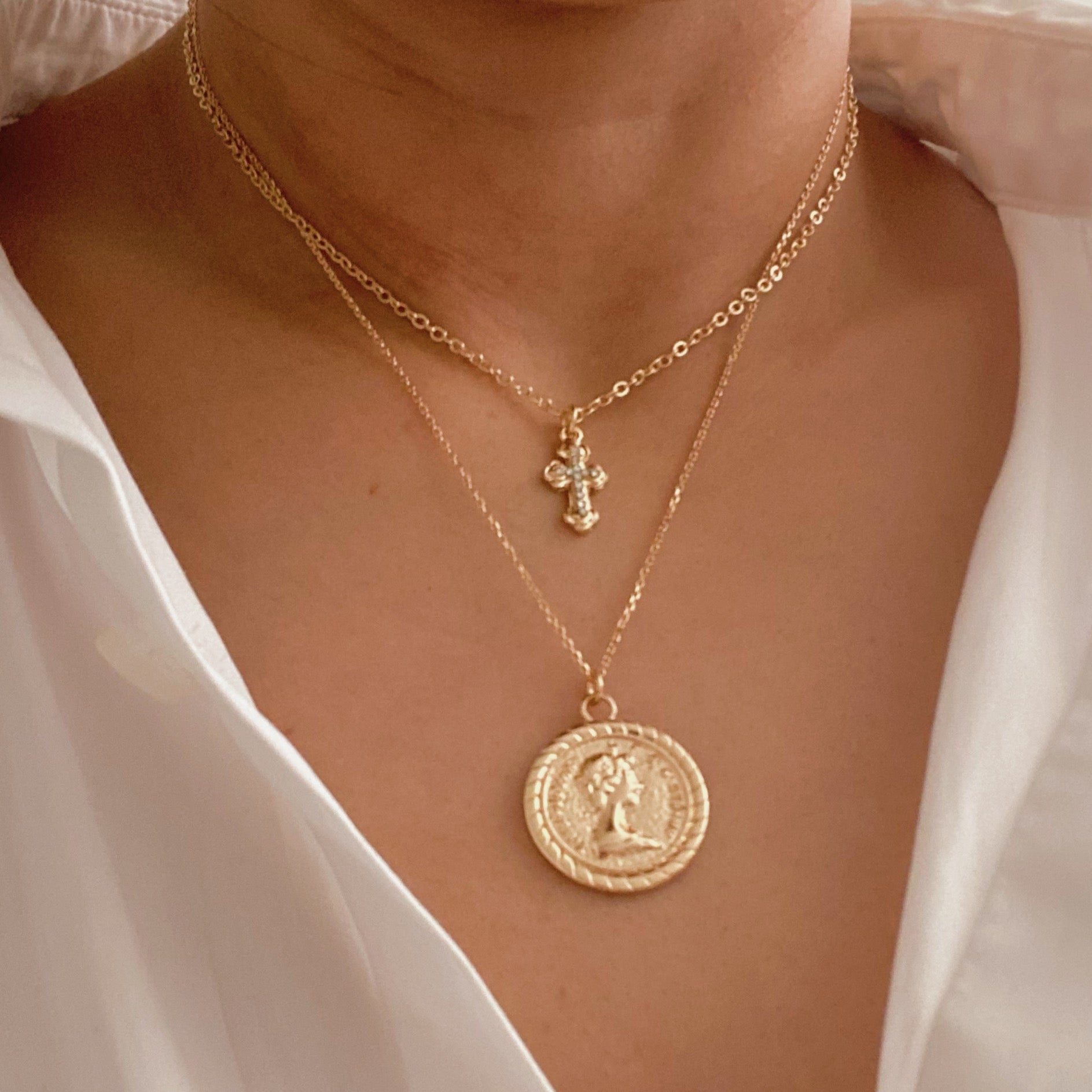 Cross and Coin Layered Necklace featuring a gold plated cross and classic coin design, elegantly layered for a stylish look.