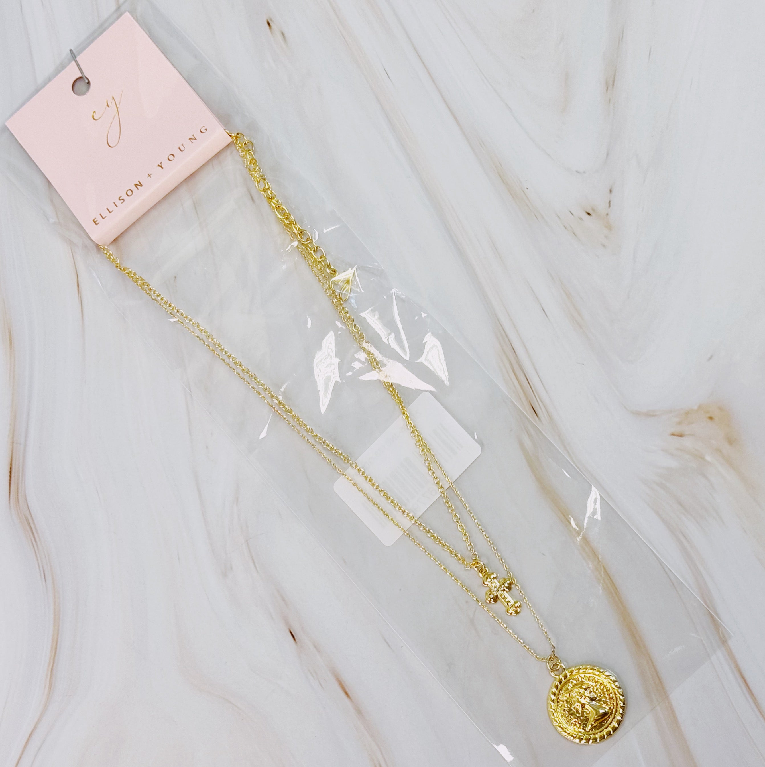 Cross and Coin Layered Necklace featuring a gold plated cross and classic coin design, elegantly layered for a stylish look.