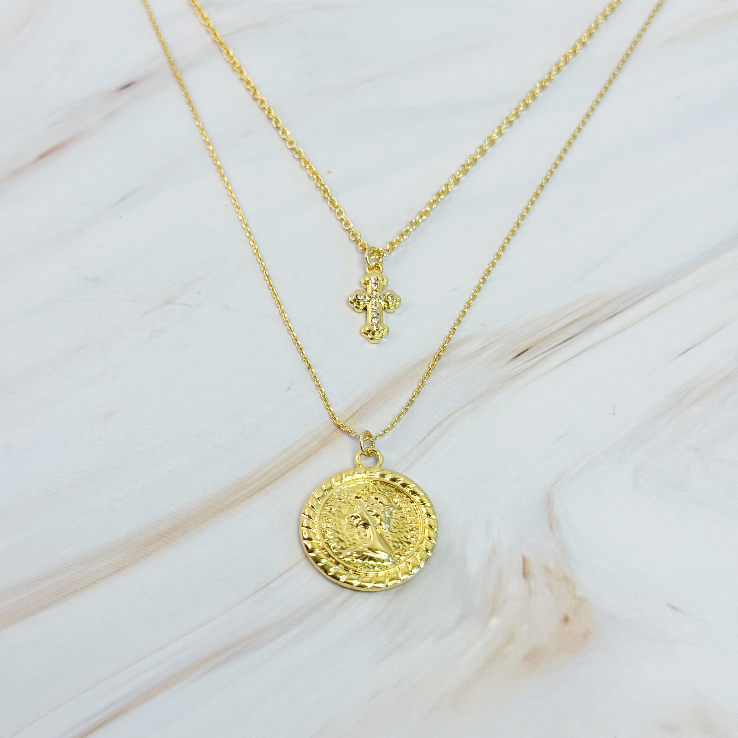 Cross and Coin Layered Necklace featuring a gold plated cross and classic coin design, elegantly layered for a stylish look.