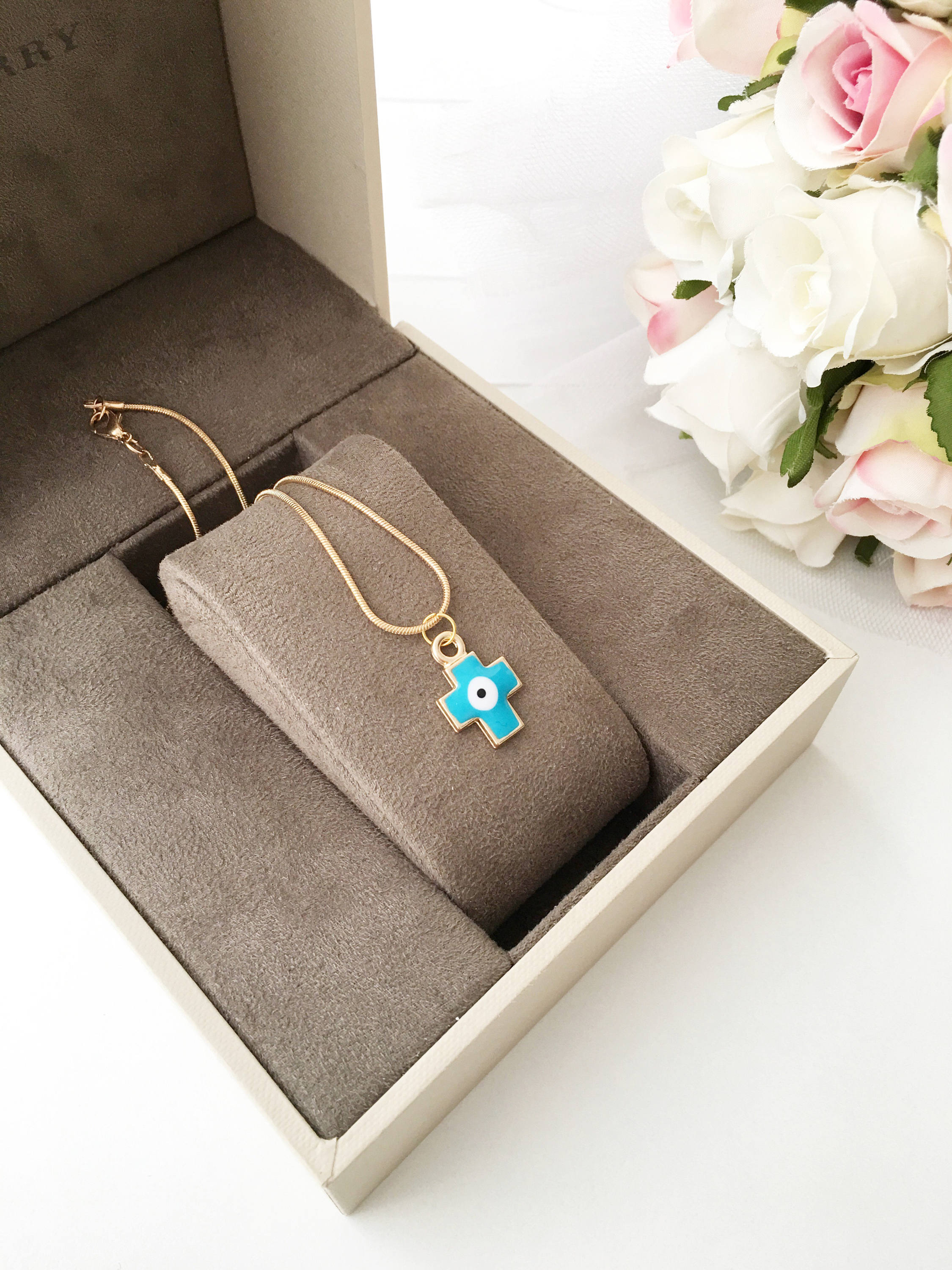 Handmade Cross Evil Eye Necklace featuring blue and red charm on a gold plated chain, symbolizing protection and spirituality.