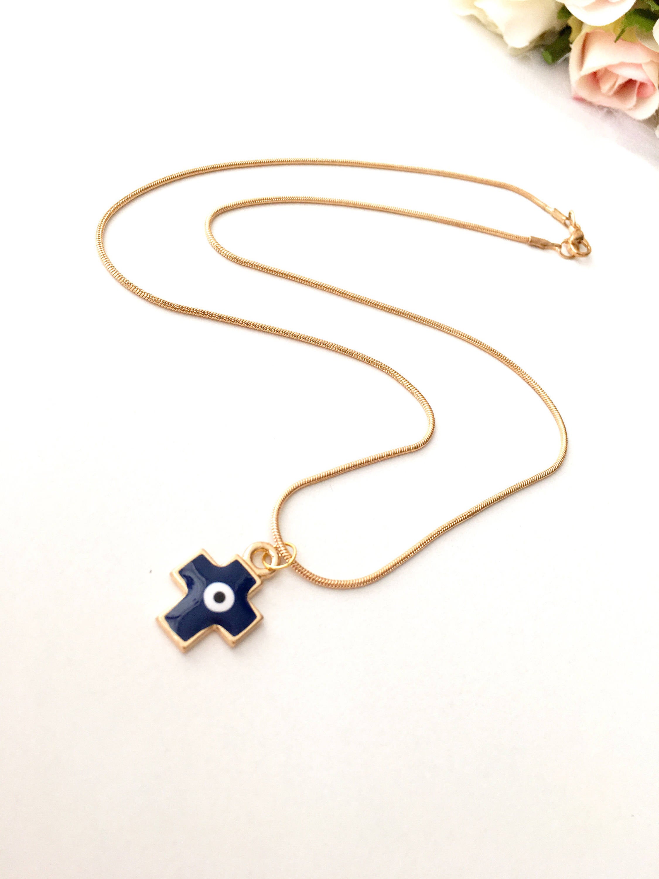 Handmade Cross Evil Eye Necklace featuring blue and red charm on a gold plated chain, symbolizing protection and spirituality.