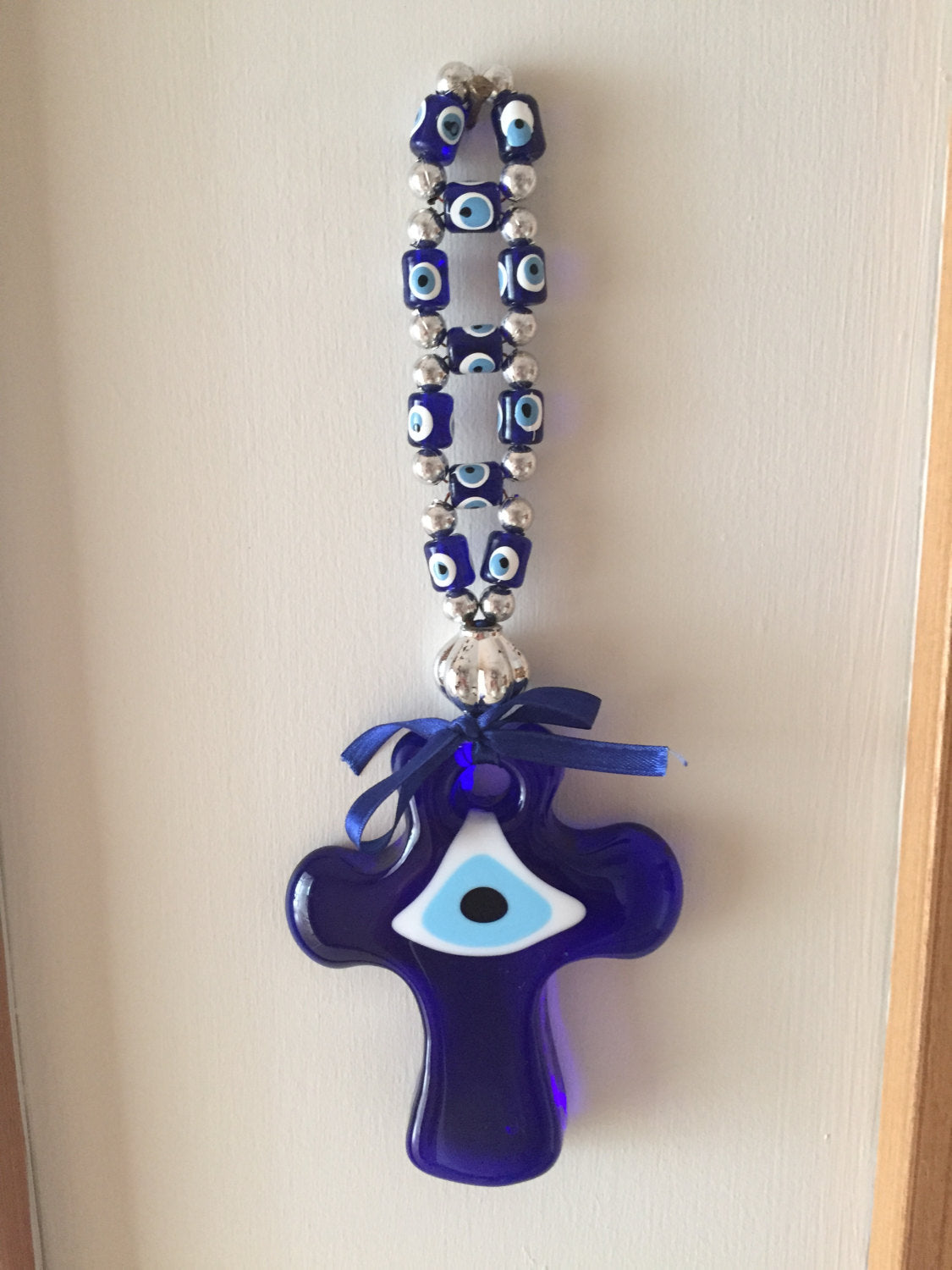 Handmade Cross Evil Eye Wall Decor featuring a large cross and small evil eye beads, symbolizing protection and style.