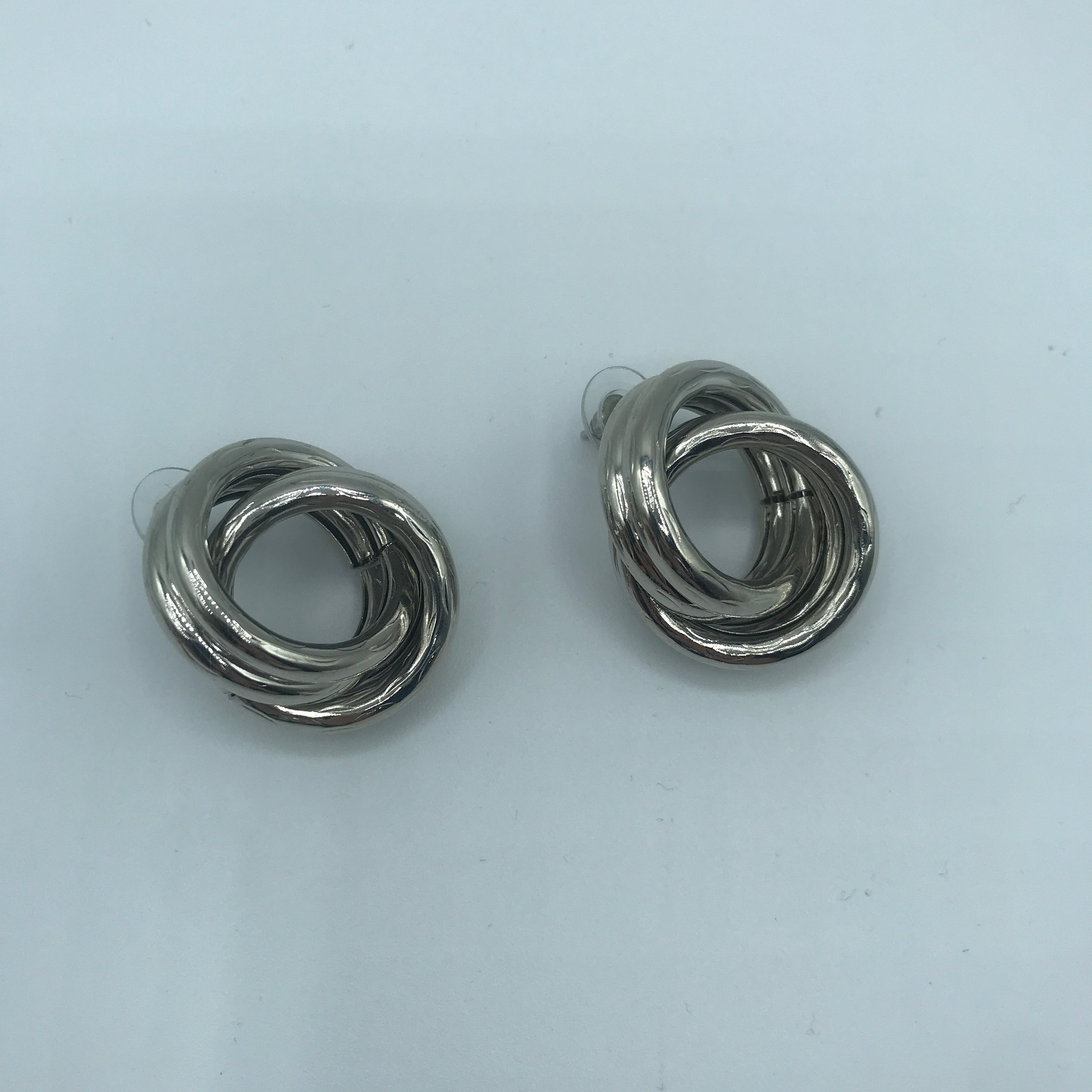 A pair of stylish crossed hoop earrings made from alloy and steel, showcasing a modern design.