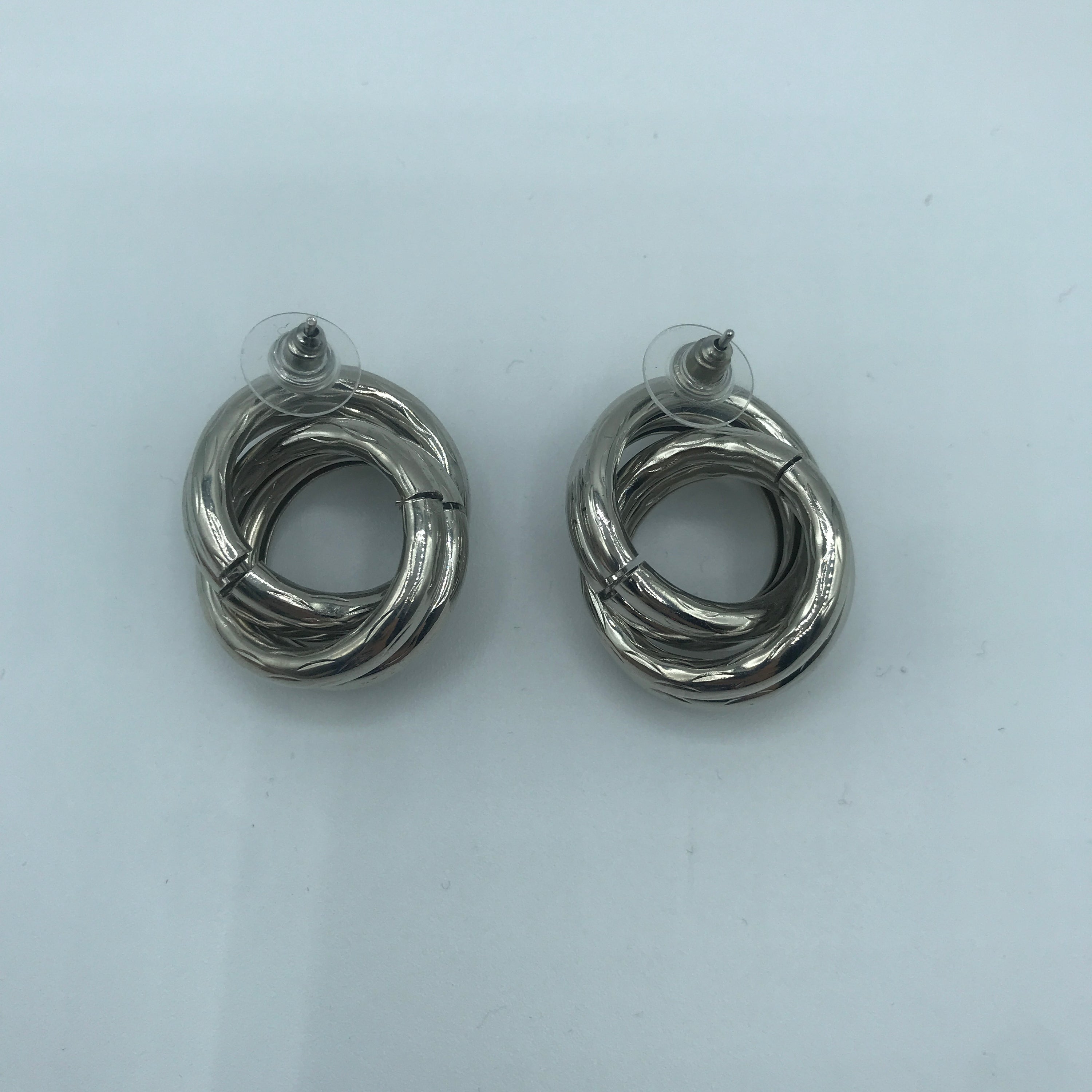 A pair of stylish crossed hoop earrings made from alloy and steel, showcasing a modern design.