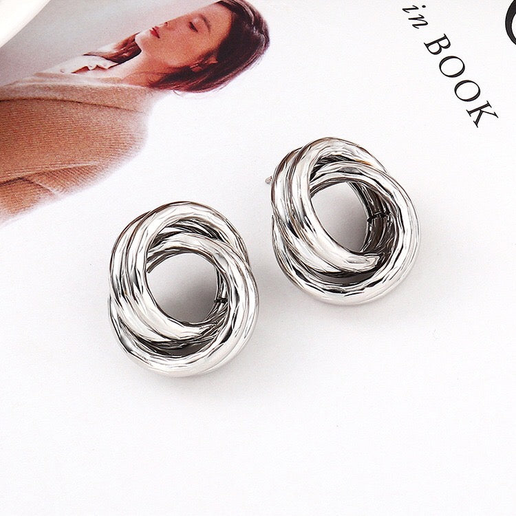 A pair of stylish crossed hoop earrings made from alloy and steel, showcasing a modern design.