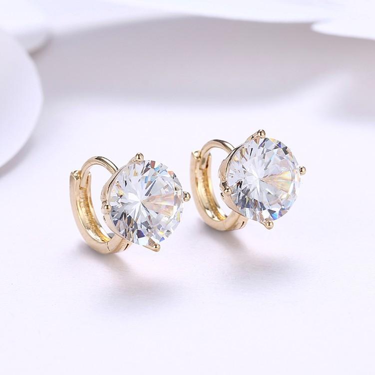 A pair of elegant crystal huggie earrings set in 18K gold, showcasing their sparkling stones and butterfly backing.