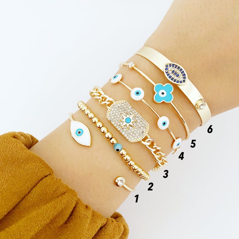 Cuff Evil Eye Bracelet featuring a white evil eye charm on a gold stainless steel cuff, showcasing its handmade craftsmanship and adjustable design.