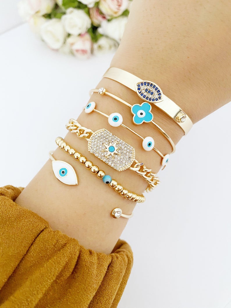 Cuff Evil Eye Bracelet featuring a white evil eye charm on a gold stainless steel cuff, showcasing its handmade craftsmanship and adjustable design.