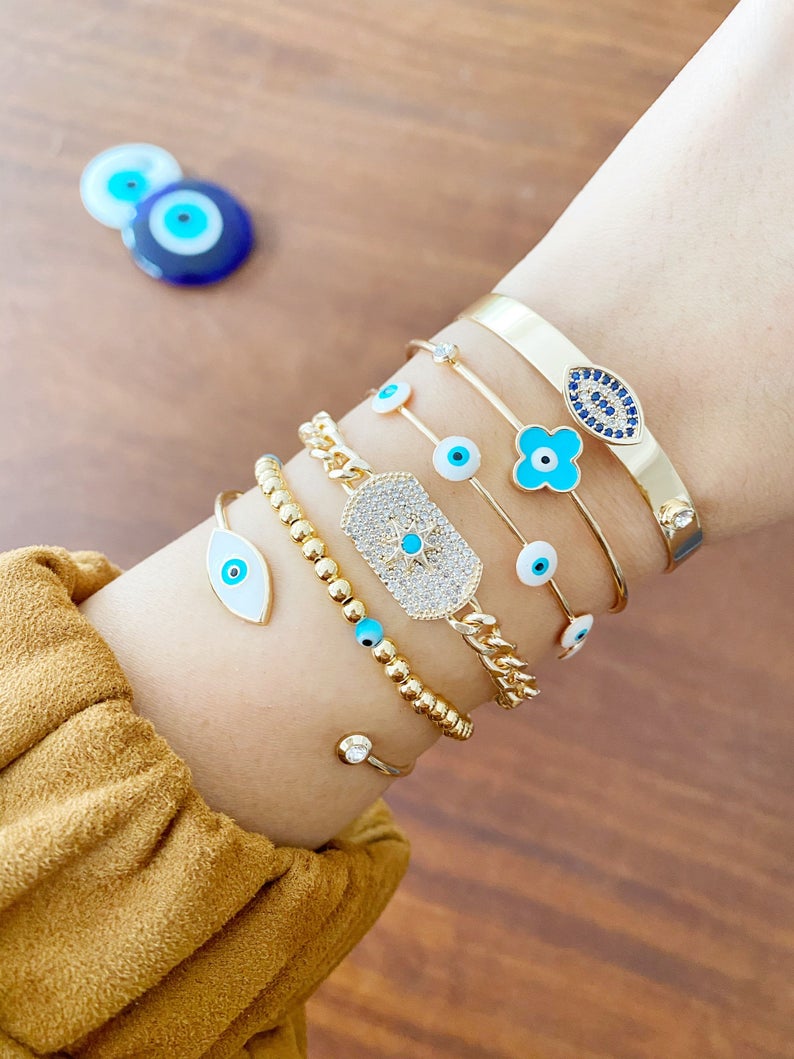 Cuff Evil Eye Bracelet featuring a white evil eye charm on a gold stainless steel cuff, showcasing its handmade craftsmanship and adjustable design.