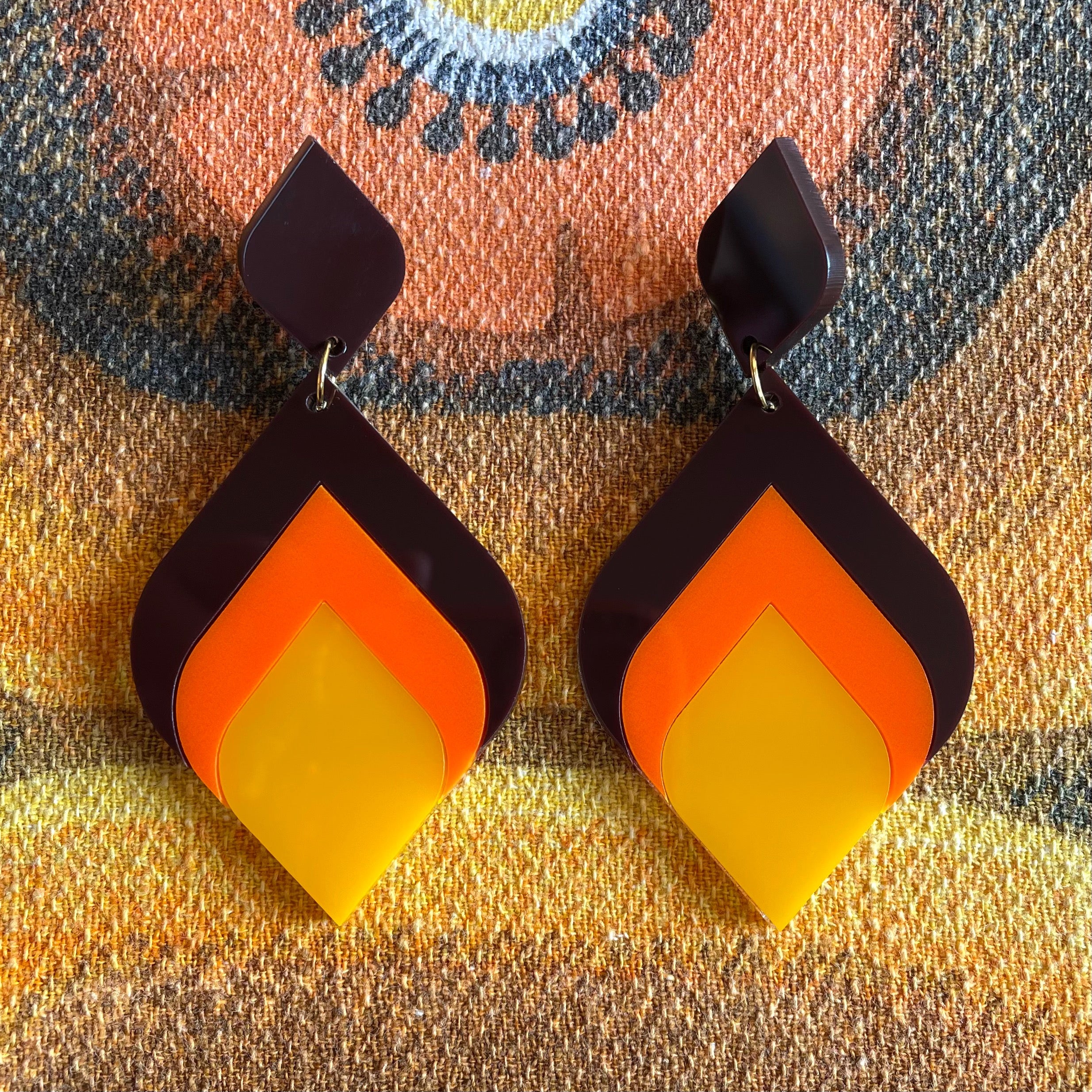 A pair of stylish Curved Diamond Earrings featuring a retro design, made from laser cut acrylic, showcasing a vibrant 70's aesthetic.