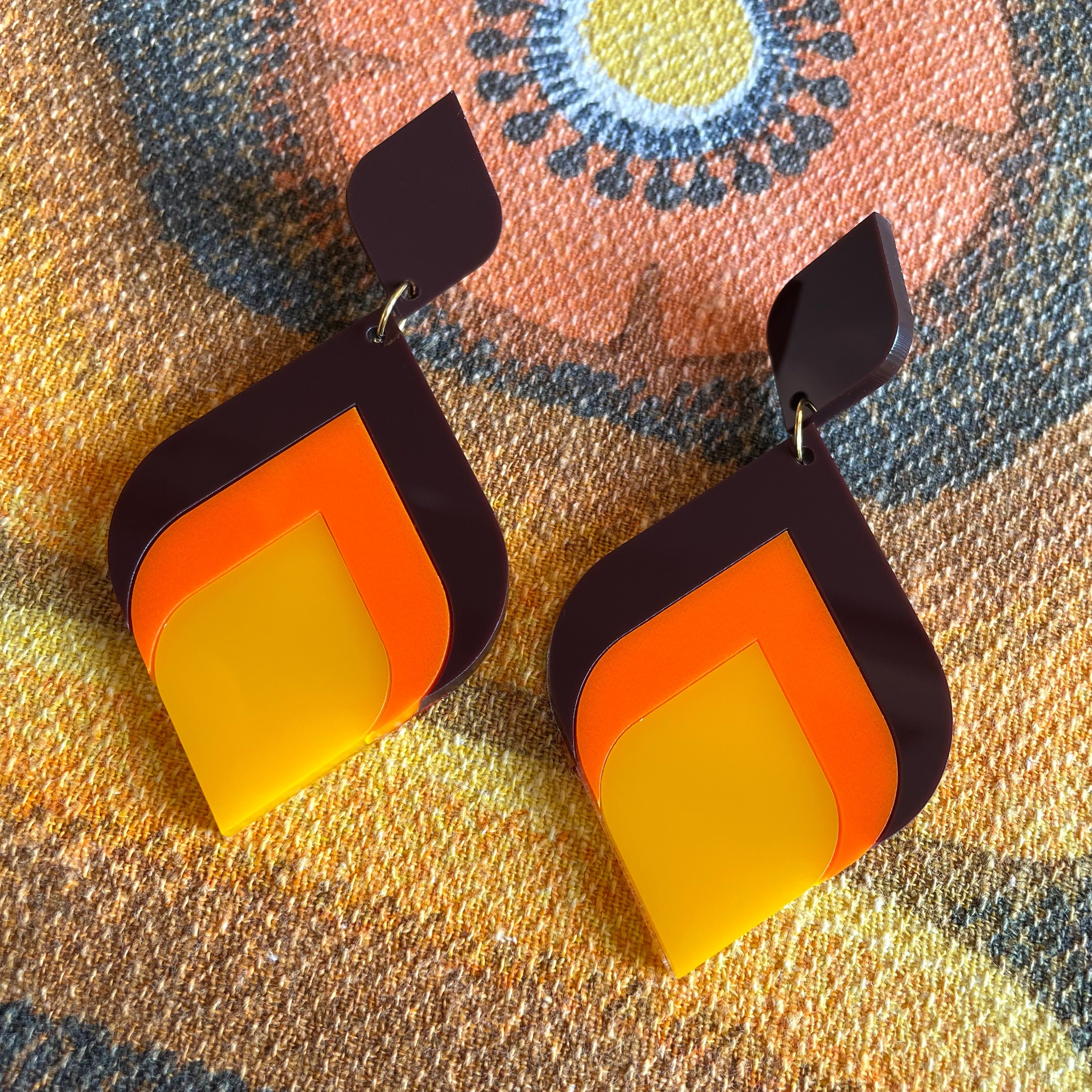 A pair of stylish Curved Diamond Earrings featuring a retro design, made from laser cut acrylic, showcasing a vibrant 70's aesthetic.