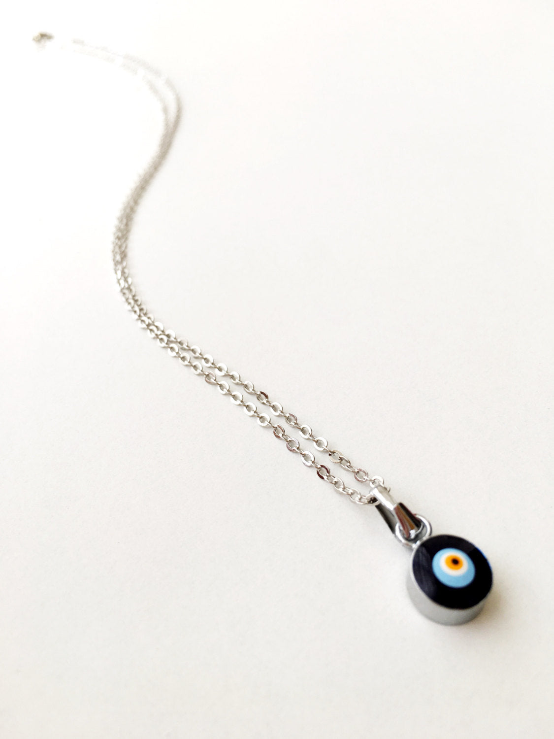 Handmade Dainty Evil Eye Necklace featuring blue glass beads and a silver chain, symbolizing protection and style.