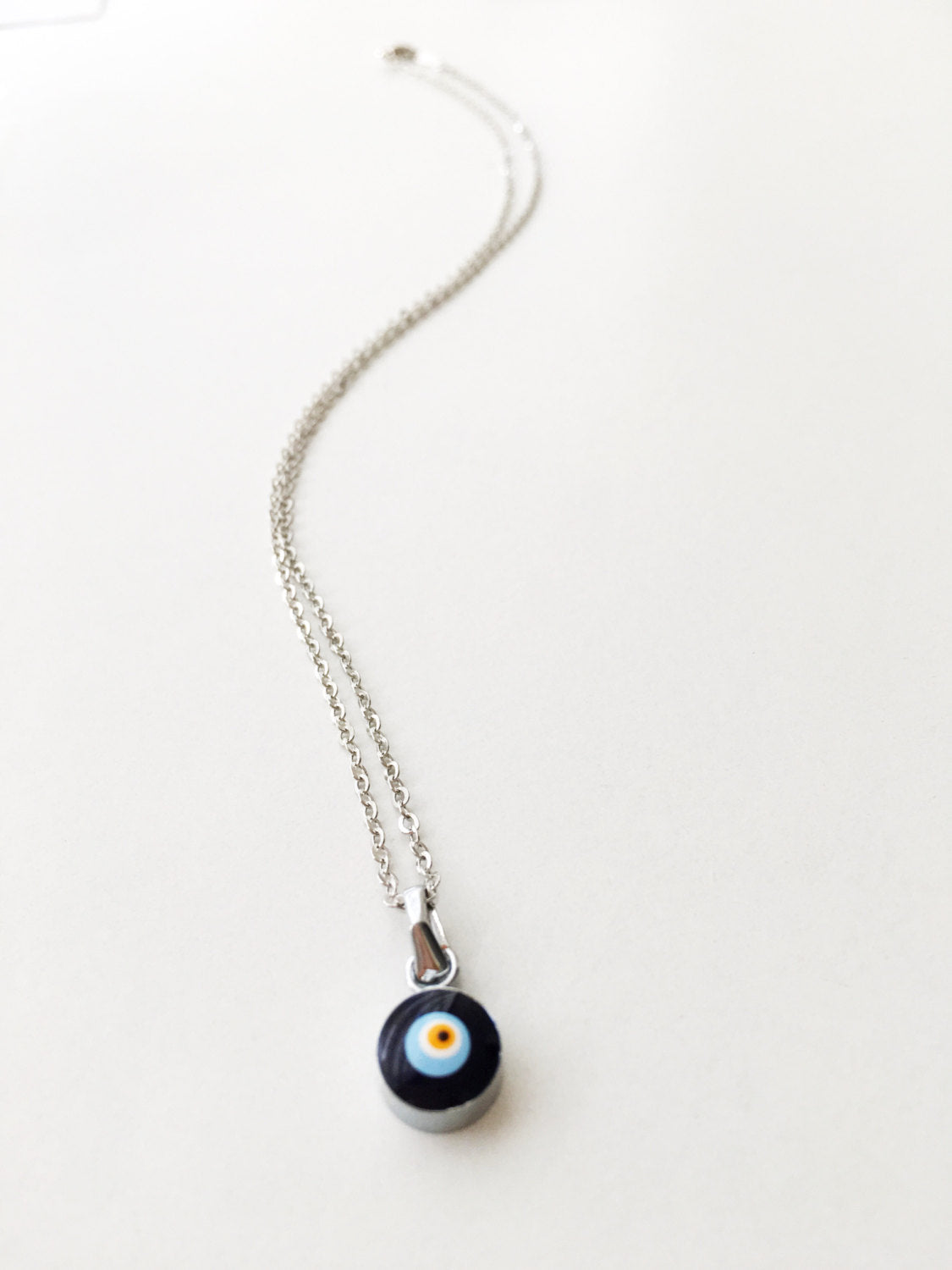 Handmade Dainty Evil Eye Necklace featuring blue glass beads and a silver chain, symbolizing protection and style.