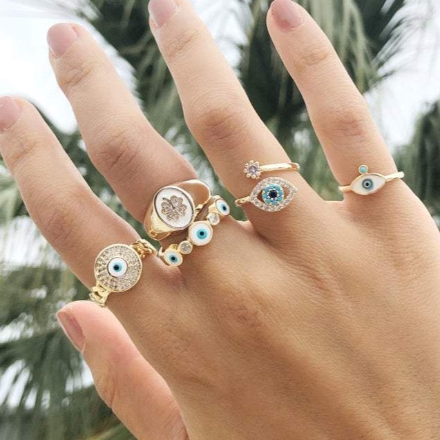 A collection of dainty adjustable evil eye rings in gold, featuring a white evil eye design, perfect for everyday wear.