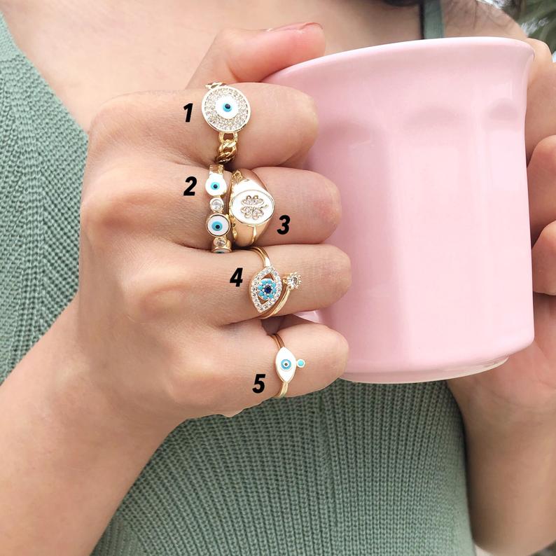 A collection of dainty adjustable evil eye rings in gold, featuring a white evil eye design, perfect for everyday wear.