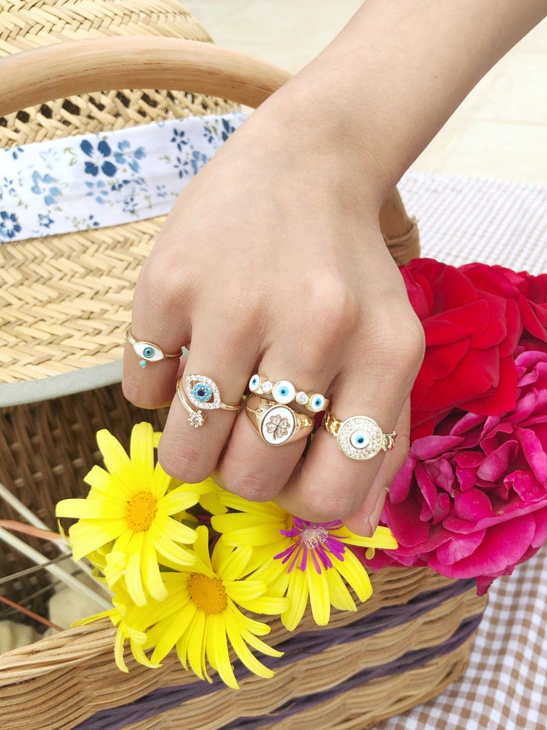 A collection of dainty adjustable evil eye rings in gold, featuring a white evil eye design, perfect for everyday wear.