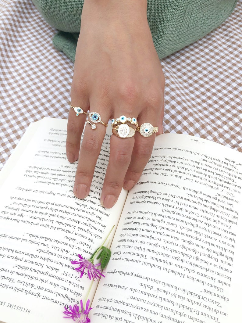 A collection of dainty adjustable evil eye rings in gold, featuring a white evil eye design, perfect for everyday wear.