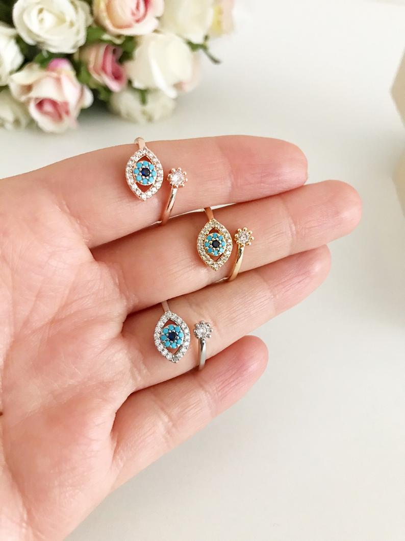 A collection of dainty adjustable evil eye rings in gold, featuring a white evil eye design, perfect for everyday wear.