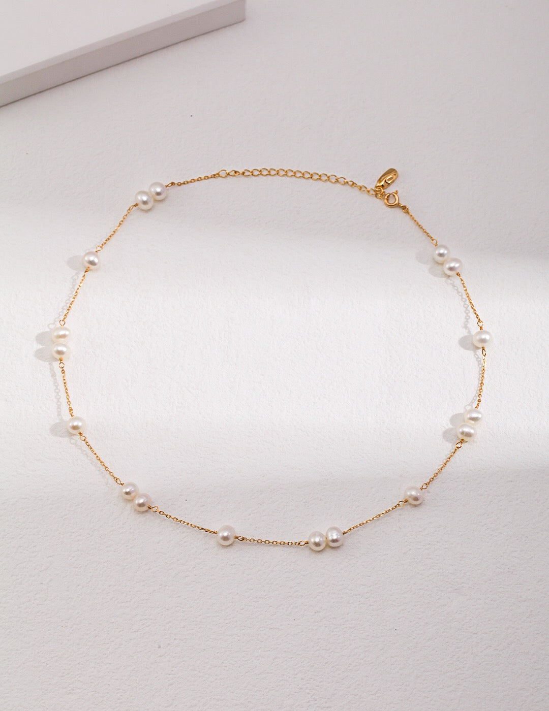 A delicate Dainty Freshwater Pearl Choker Necklace featuring genuine pearls and sterling silver, elegantly displayed on a soft fabric background.