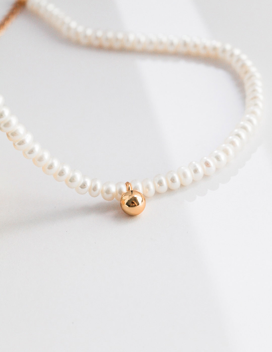 A delicate Dainty Pearl Beaded Necklace featuring natural pearls and gold vermeil, elegantly displayed on a soft fabric background.