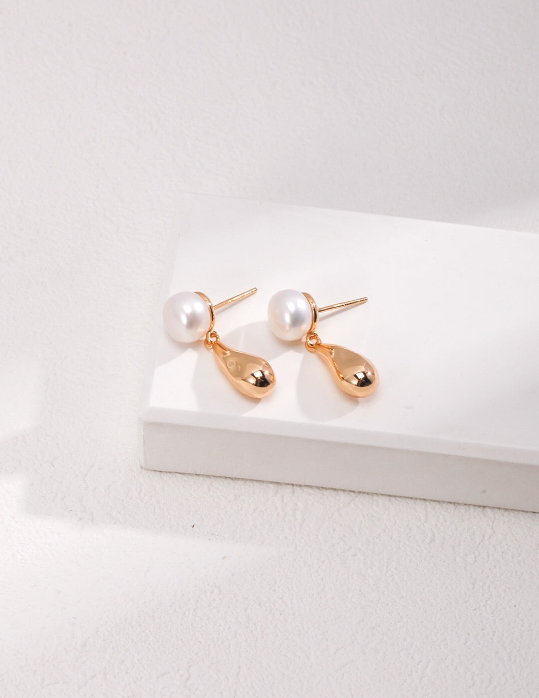 A pair of elegant Dainty Raindrop Earrings featuring natural pearls and gold vermeil, showcasing their delicate design.