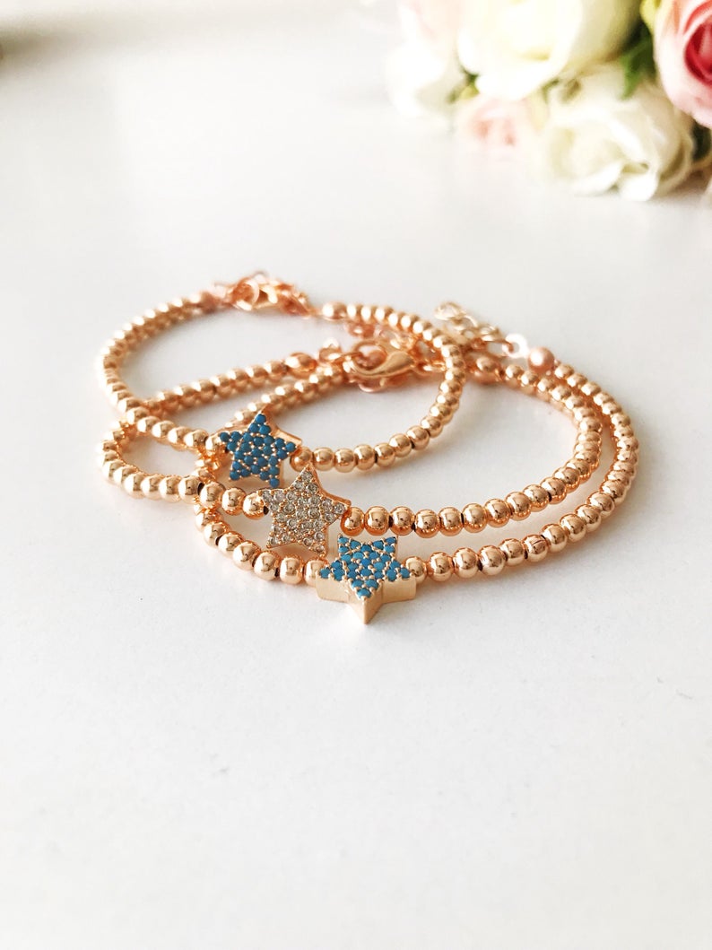 A dainty rose gold bracelet featuring a tiny star charm, adorned with either turquoise or zirconia beads, showcasing its delicate and adjustable design.