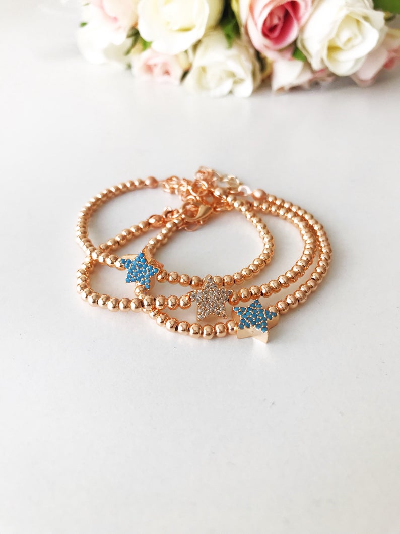 A dainty rose gold bracelet featuring a tiny star charm, adorned with either turquoise or zirconia beads, showcasing its delicate and adjustable design.