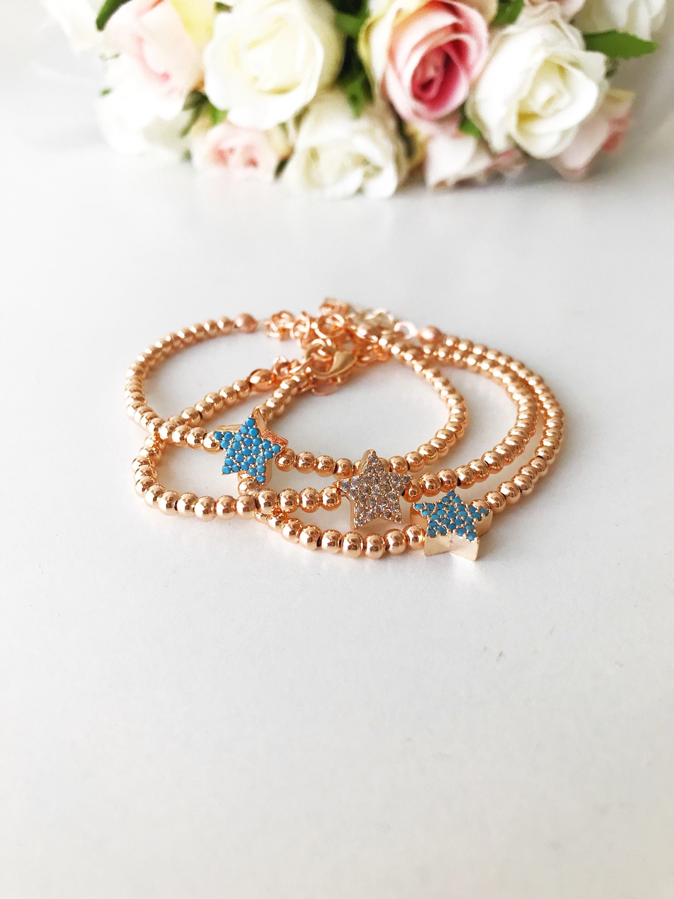 A dainty rose gold bracelet featuring a tiny star charm, adorned with either turquoise or zirconia beads, showcasing its delicate and adjustable design.