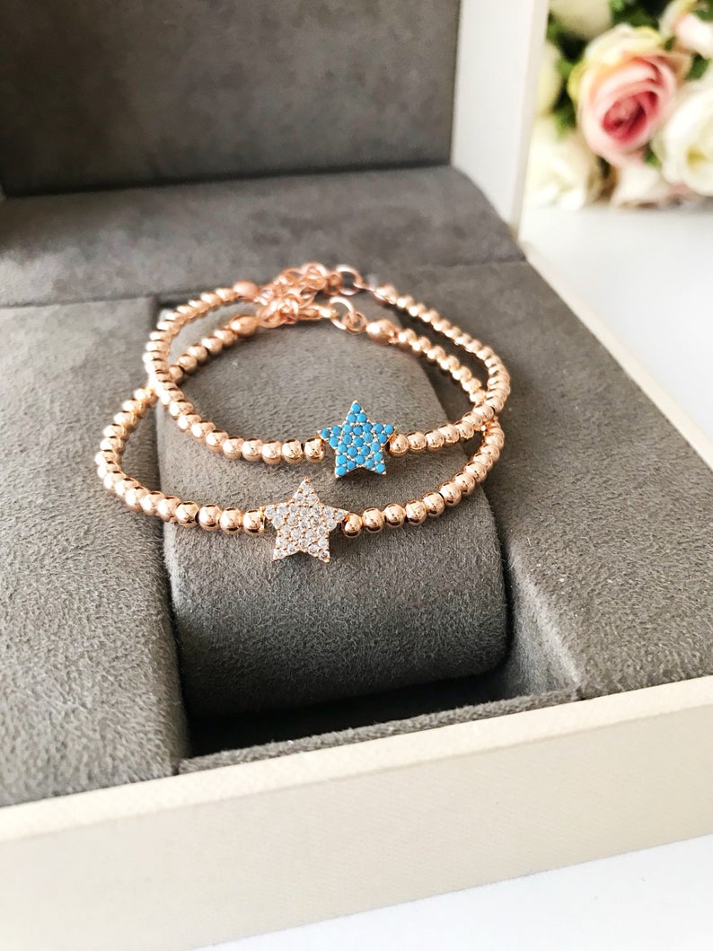 A dainty rose gold bracelet featuring a tiny star charm, adorned with either turquoise or zirconia beads, showcasing its delicate and adjustable design.