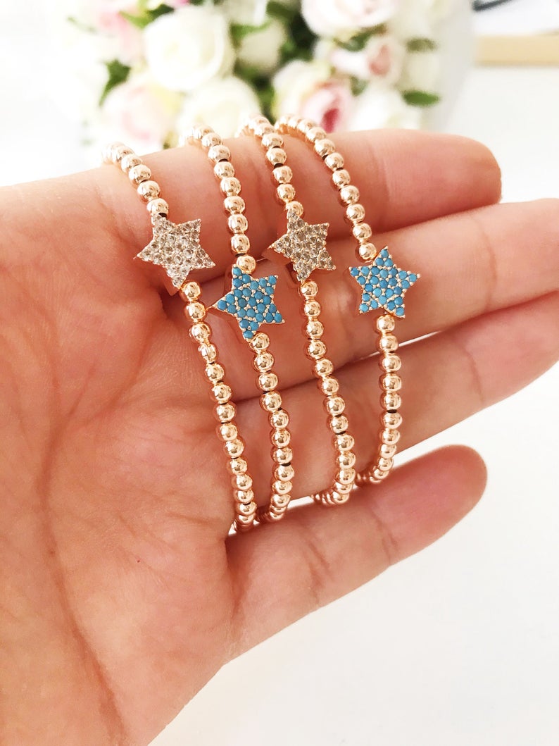 A dainty rose gold bracelet featuring a tiny star charm, adorned with either turquoise or zirconia beads, showcasing its delicate and adjustable design.