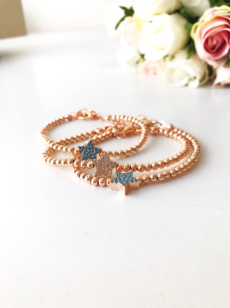 A dainty rose gold bracelet featuring a tiny star charm, adorned with either turquoise or zirconia beads, showcasing its delicate and adjustable design.